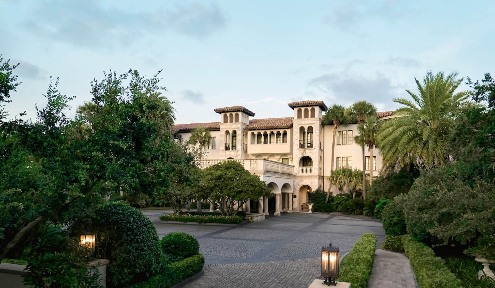 A cloister exterior framed by palms, used as an editorial travel setting.